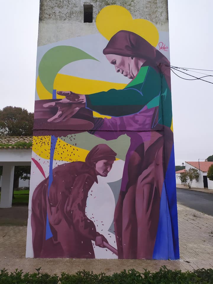 Mural en el que se pude ver a dos mujeres con vestimenta del siglo pasado labrando la tierra y trillando el grano recogido